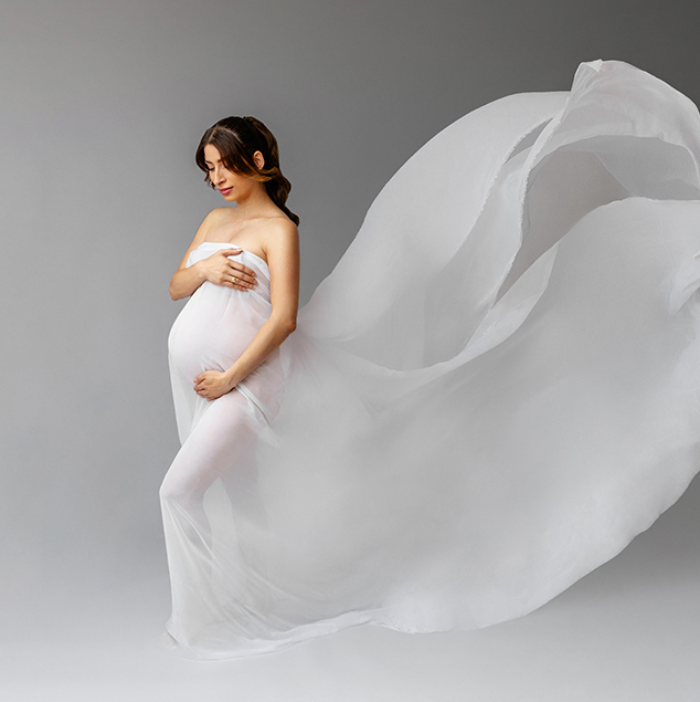 Elegantes Babybauch Shooting im Studio mit fließendem weißen Kleid und sanftem Licht, stilvolle Schwangerschaftsfotografie